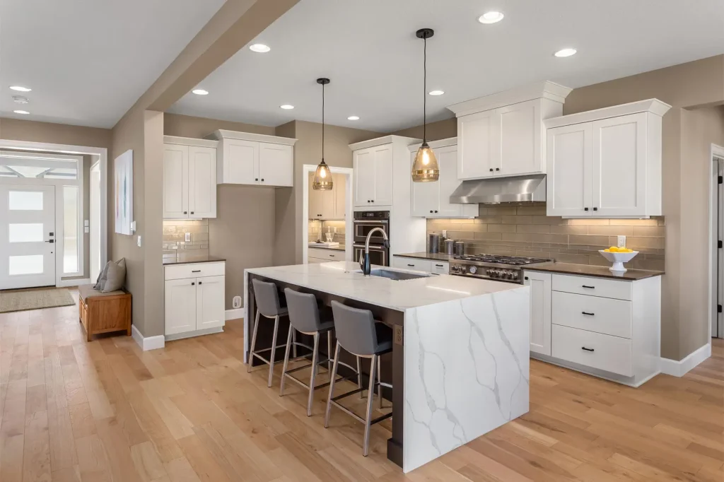 Beautiful kitchen in new luxury home with waterfall island, quartz counter tops, farmhouse sink, and hardwood floors.