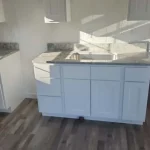 Corner of a modern kitchen with granite countertops and freshly white painted cabinetry.