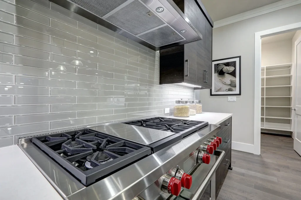 Modern gray kitchen features steel stove with a hood.