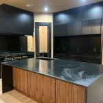 Modern kitchen with black granite countertops and black painted cabinetry.