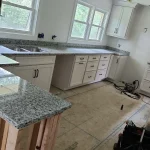 Modern kitchen with granite countertops and white painted cabinetry.