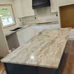 Modern kitchen with marble countertop island and white painted cabinetry.