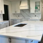 Modern kitchen with marble countertops, kitchen island and white painted cabinetry.